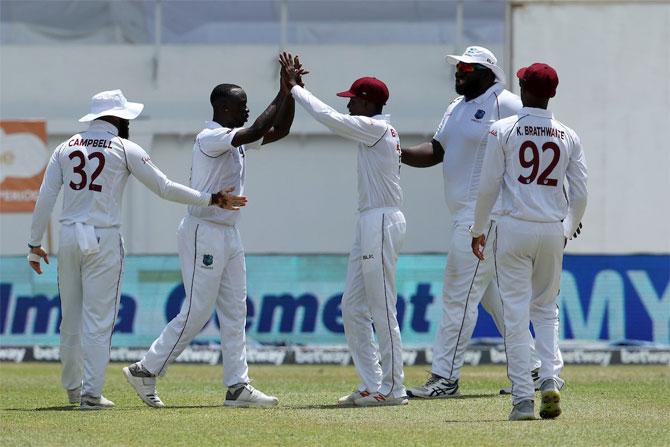 Kemar Roach celebrates with teammates after dismissing Virat Kohli for a duck