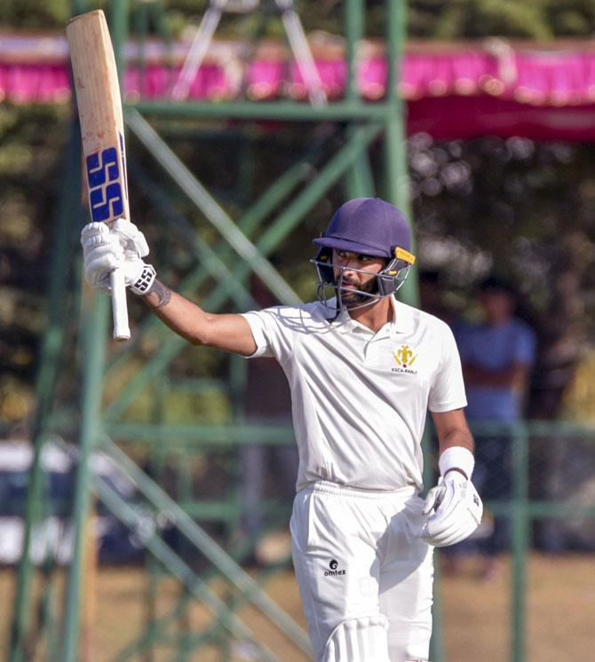 Karnataka batsman Siddharth K V raises his bat after completing his half-century 