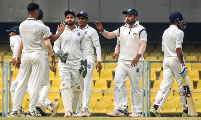 Maharashtra cricketers celebrate the dismissal of Assam’s batsman Rahul Hazarika (Right) on the first day of their Ranji Trophy cricket match at Barsapara in Guwahati on Sunday