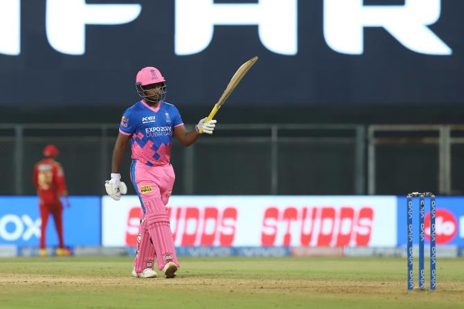 Sanju Samson raises his bat in celebration of his hundred.