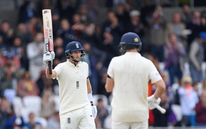 Joe Root waves to the dressing room after completing 50.