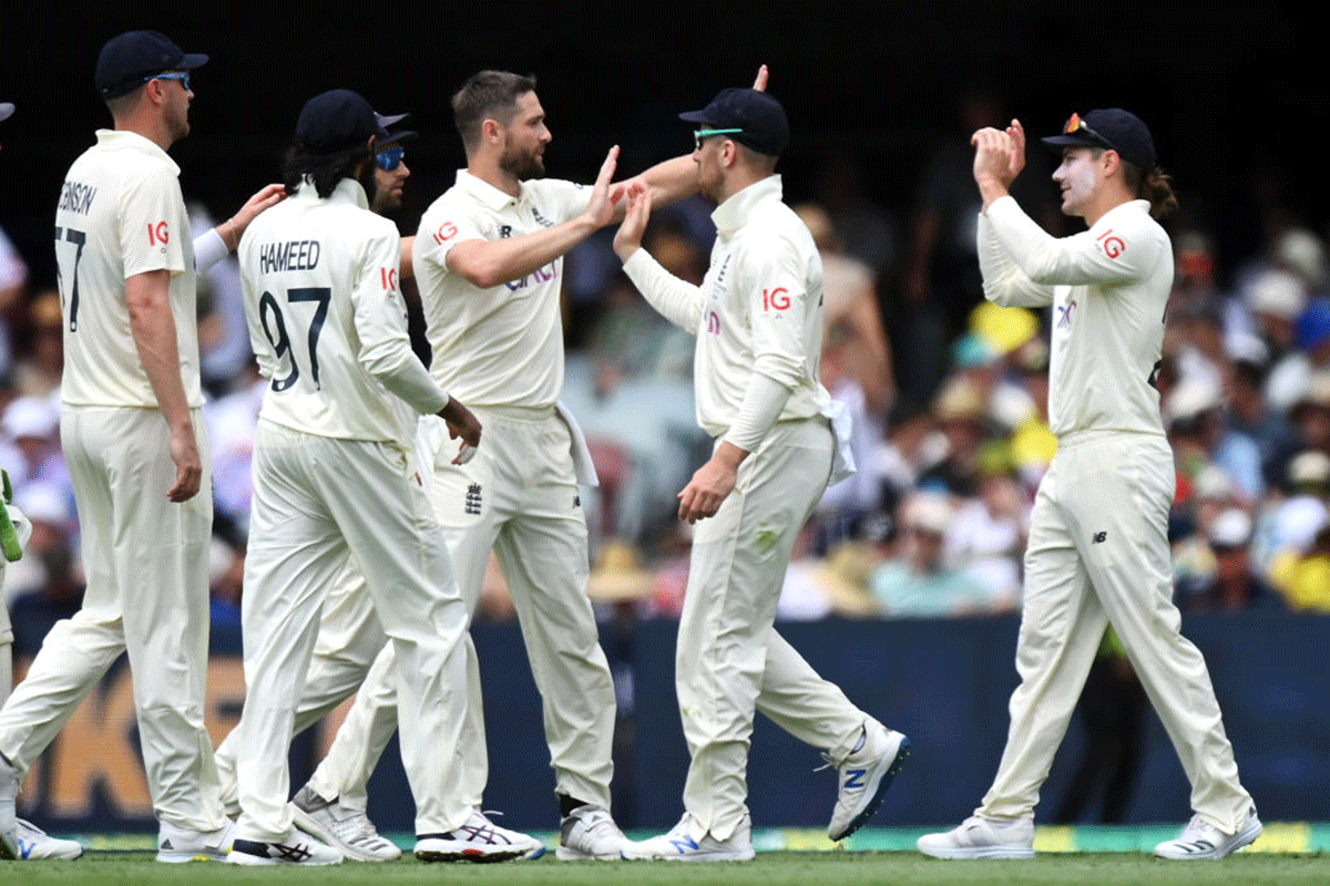 England's Chris Woakes and Rory Burns celebrate with their team after combining to take the wicket of Australia's Mitchell Starc