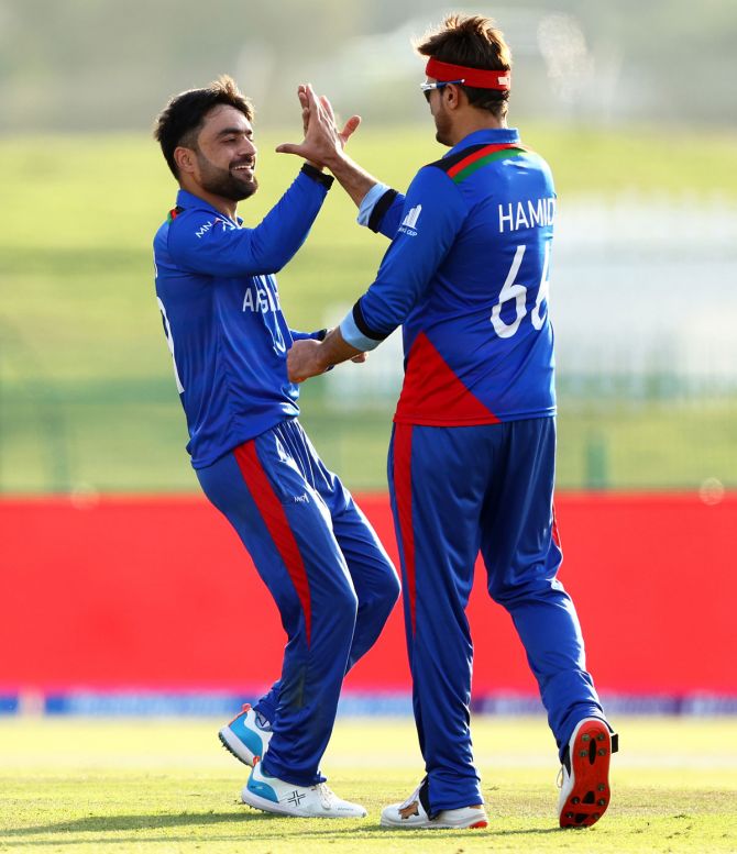 Rashid Khan celebrates with teammate Hamid Hassan after dismissing New Zealand opener Martin Guptill.