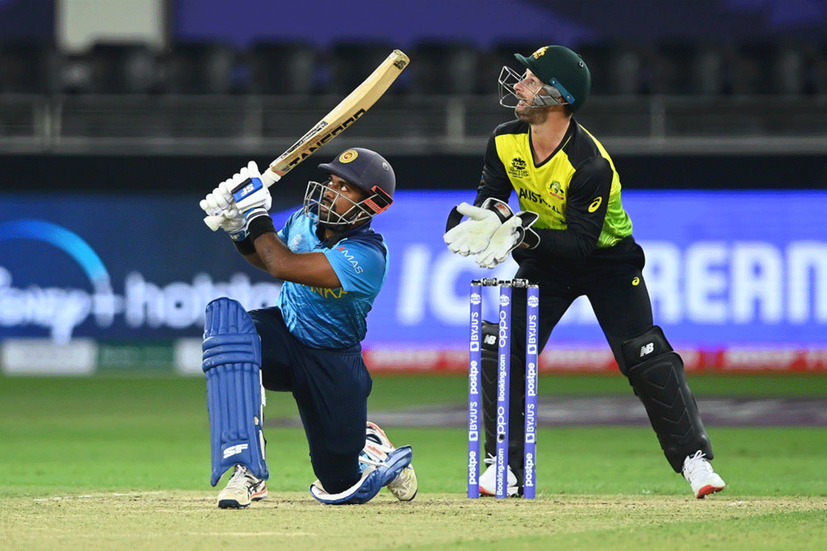 Charith Asalanka sends the ball past the boundary rope as Australia's wicketkeeper Matthew Wade looks on.