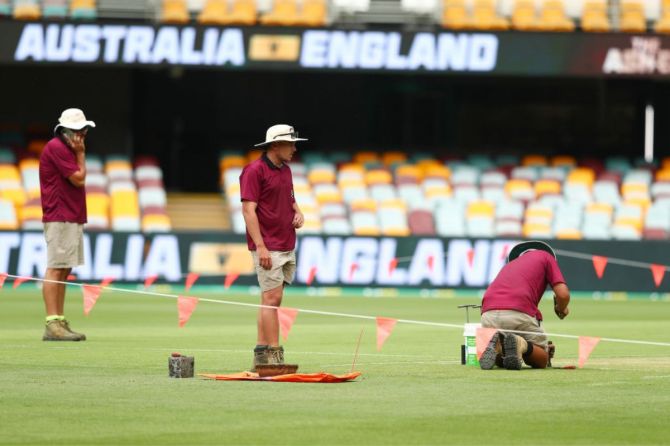 Ground staff work on the pitch at The Gabba
