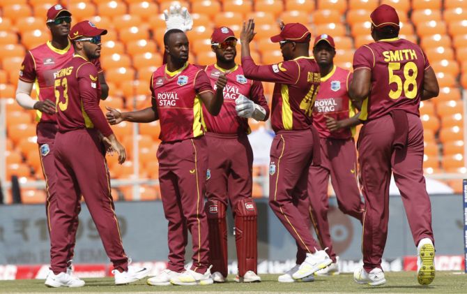 West Indies pacer Kemar Roach celebrates with teammates after dismissing India opener Rohit Sharma.