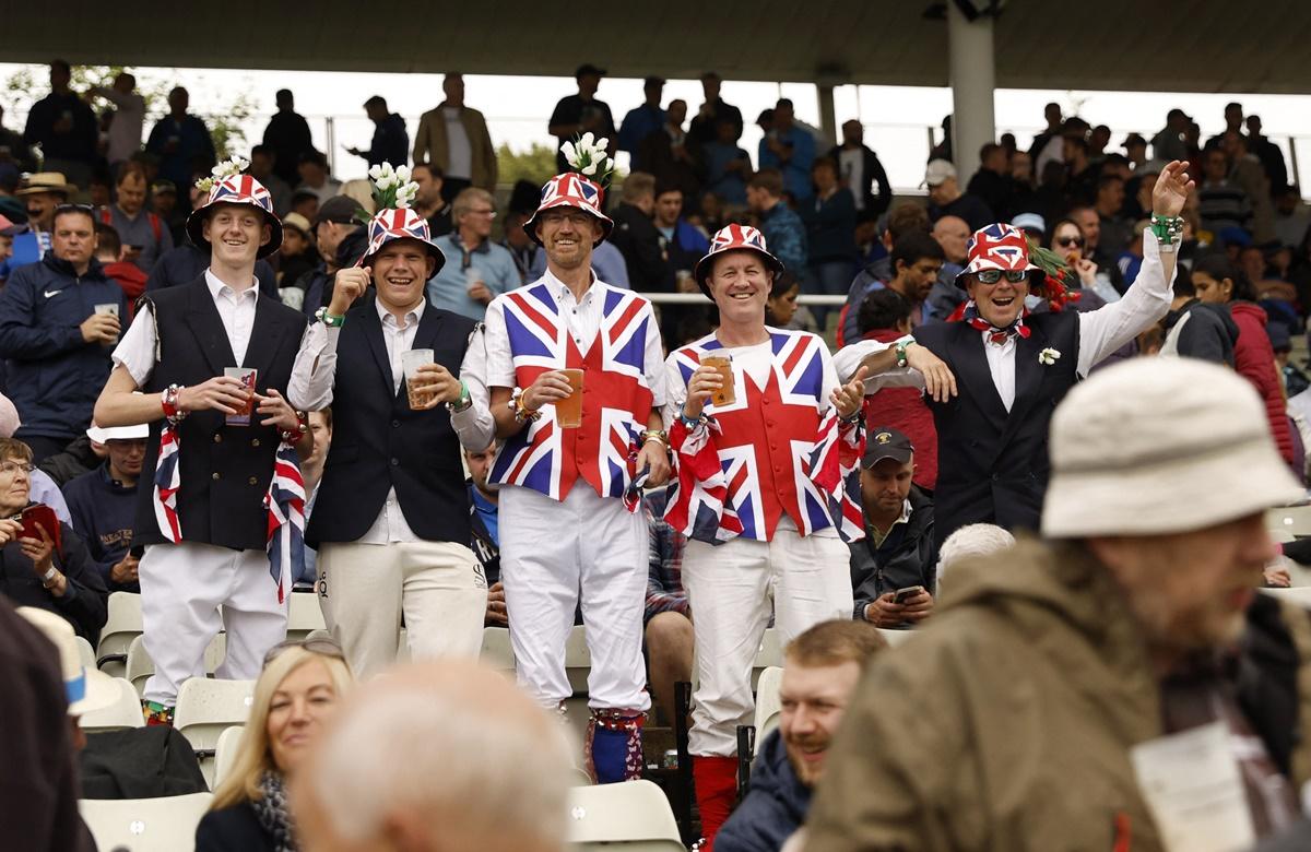 Fans wearing the Union Jack sing in the stands.