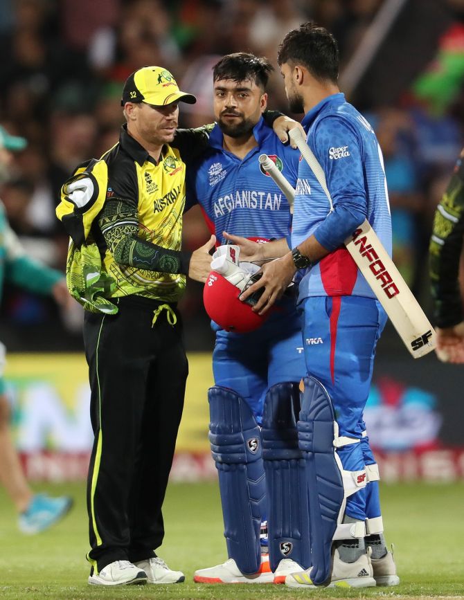 David Warner congratulates Afghanistan's Rashid Khan on his magnificent 48 off 23 balls, which included 3 fours and 4 sixes, as Naveen ul haq Murid looks on, after the T20 World Cup match at the Adelaide Oval on Friday.