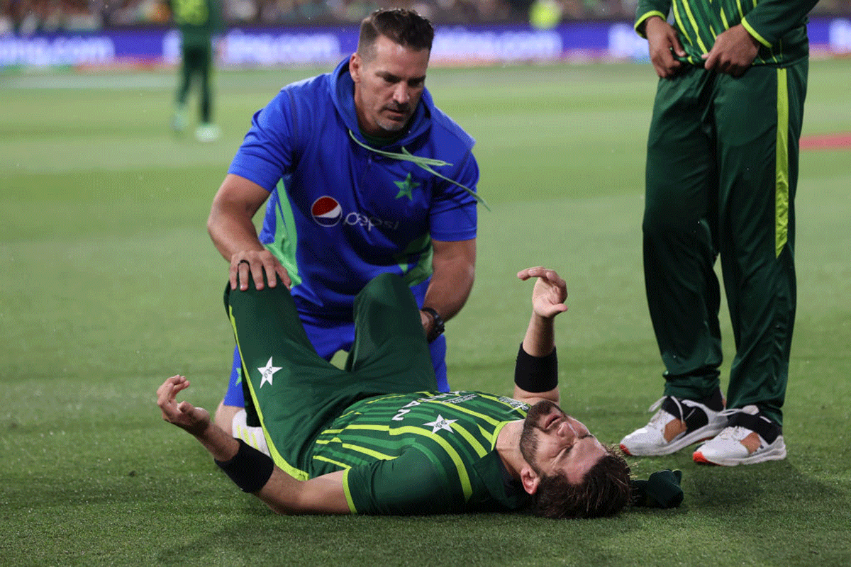 Pakistan's Shaheen Shah Afridi grimaces as he is checked by the physio after sustaining an injury while fielding during the final on Sunday
