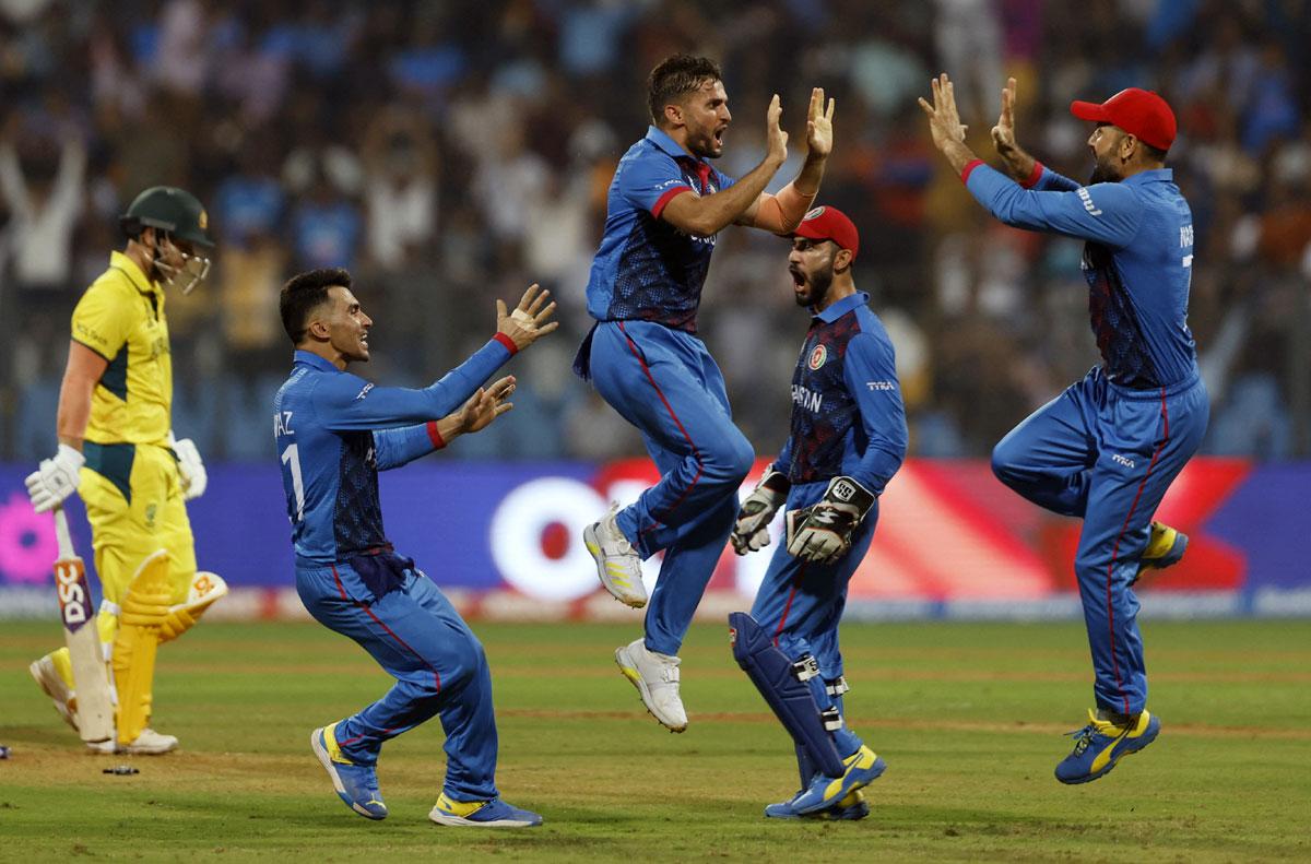 Afghanistan's Azmatullah Omarzai celebrates with teammates after taking the wicket of Australia opener David Warner.