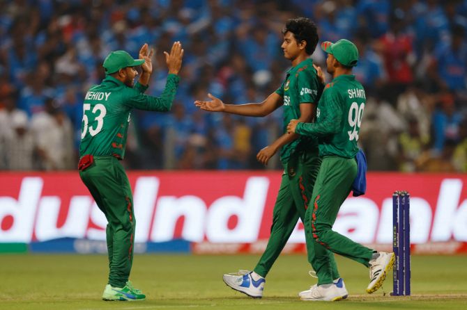 Bangladesh's Hasan Mahmud celebrates with Mehidy Hasan Miraz and Nazmul Hossain Shanto after taking the wicket of India's Rohit Sharma.