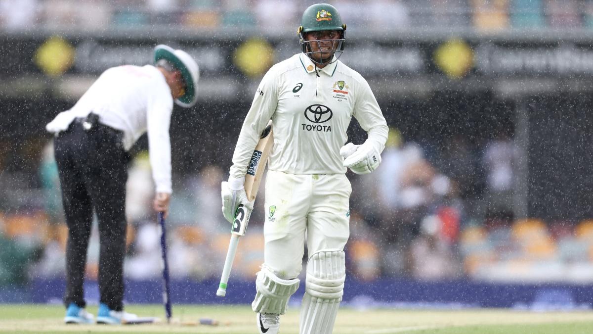 Australia opener Usman Khawaja walks off the pitch as a heavy downpour ends the morning session