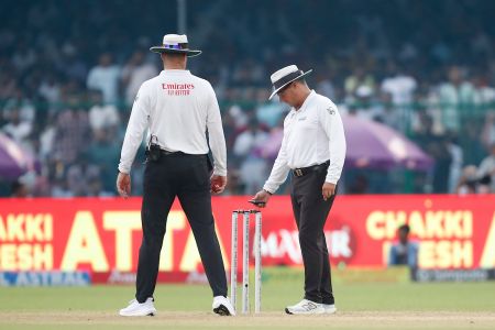  Umpires use a light meter to check the light on the field before rain halts play on Day 1