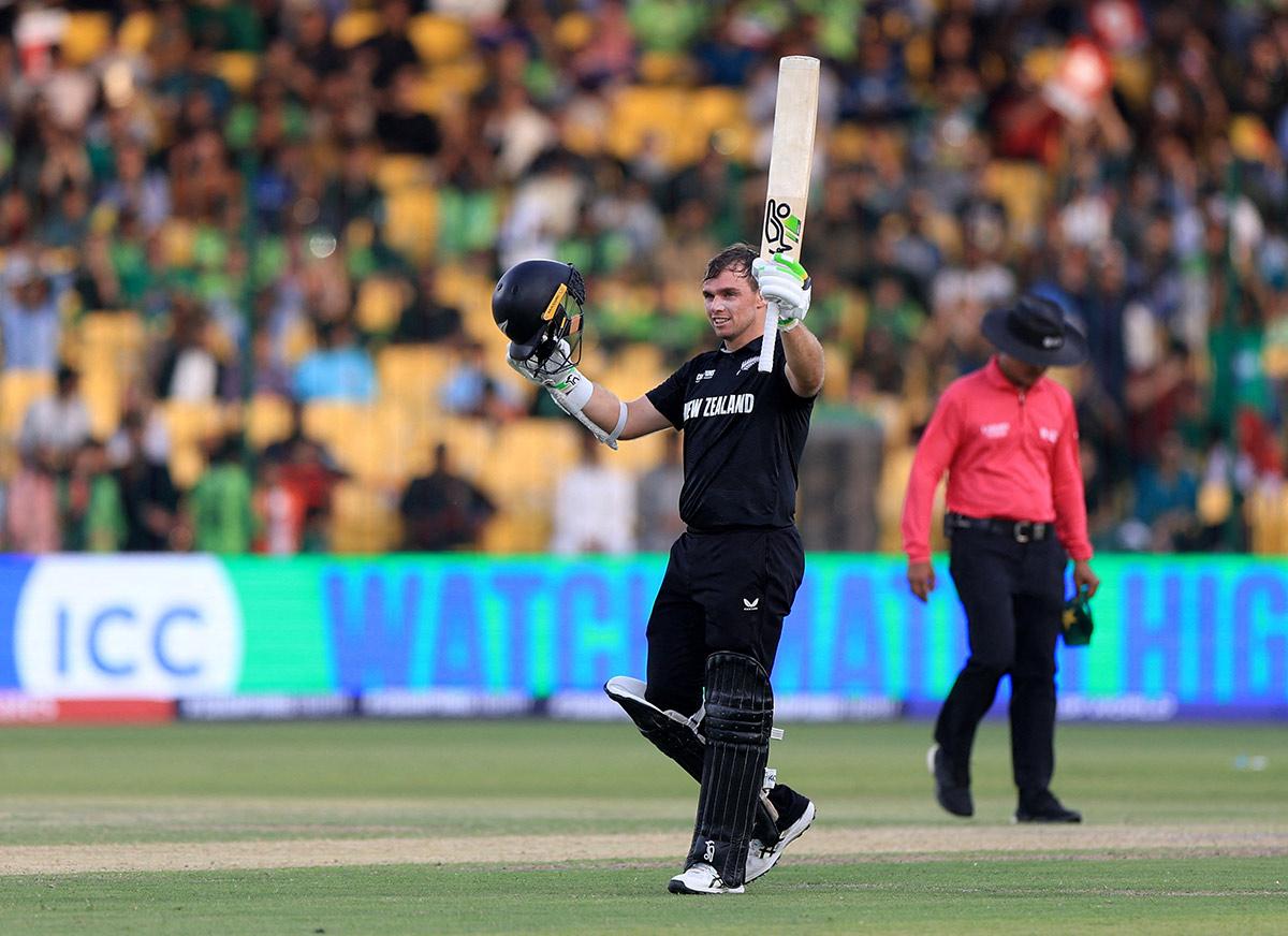 Tom Latham raises his bat to acknowledge the crowd and celebrate his century