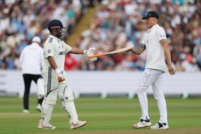  England's Brydon Carse hands over the bat back to India's Rishabh Pant after it slips from his grip as he walks back to the pavilion after losing his wicket