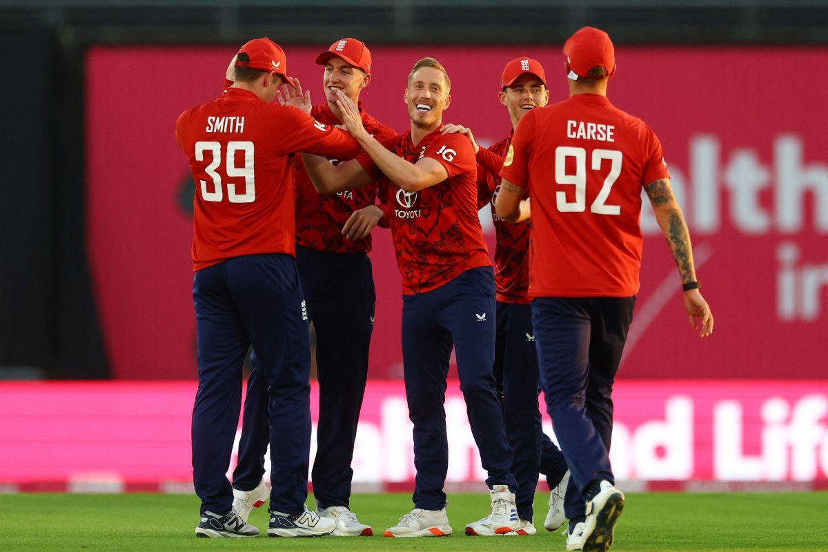 England's Luke Wood celebrates with teammates after taking the wicket of West Indies' Johnson Charles