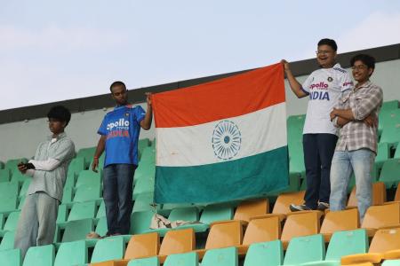 Fans raise the Indian flag during the national anthem ahead of Day 1 in the second Test between India and South Africa at the ACA stadium, in Guwahati, on Saturday, November 22, 2025.