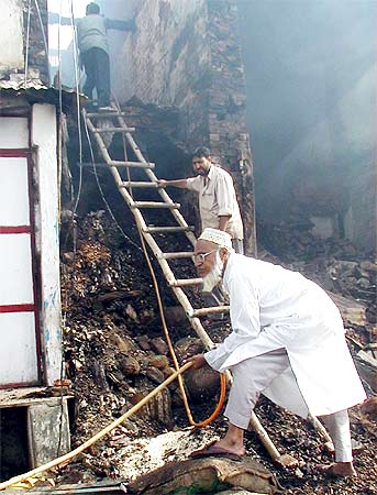 A survivor of the 2002 riots in Gujarat rifles through what is left of his shop on July 7, 2002