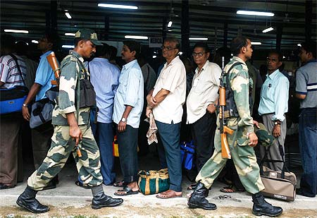 Security personnel walk past polling officers waiting to collect EVMs in Kolkata