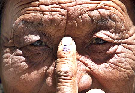 A voter shows her ink-marked finger after she cast her ballot, outside a polling station
