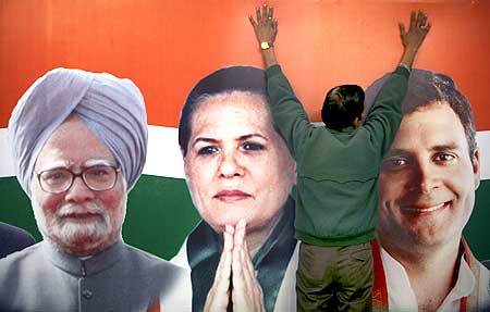 A party worker installs hoarding showing pictures of Dr Manmohan Singh, Congress Chief Sonia Gandhi and her son Rahul Gandhi