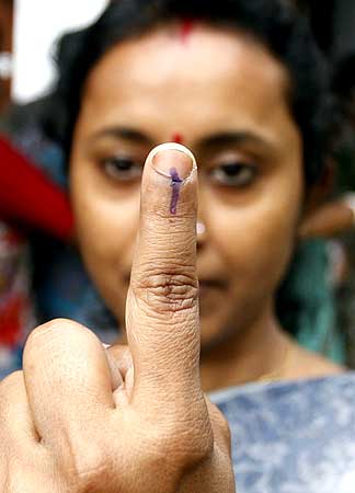 A voter shows the indelible ink mark on her finger after casting her ballot at a polling booth
