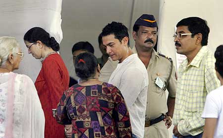 Bollywood star Aamir Khan speaks with local residents while waiting in a queue to cast his vote
