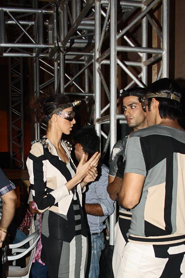 Alesia Raut in conversation with two male models backstage as they ready for a show