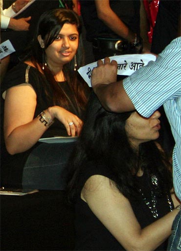 A supporter helps a member in the audience to wear a cap