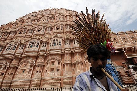 A vendor plays a flute as he tries to attract people to buy flutes in front of Hawa Mahal, also known as Palace of Winds in Jaipur, capital of India's desert state of Rajasthan, August 15, 2010. Hawa Mahal was built in 1799 by Maharaja Sawai Pratap Singh, designed by Lal Chand Usta in the form of the crown of Hindu Lord Krishna and has five stories and is constructed of red and pink sandstone. The side facing the street outside the palace complex has 953 small windows.