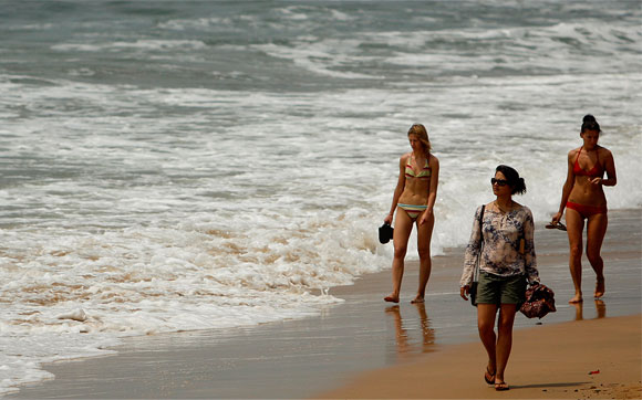Tourists walk on the Anjuna beach