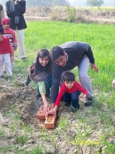 Pooja, Shashank and their son laying the foundation stone for the school building