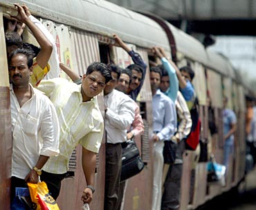 Commuters lean out of a train in Mumbai