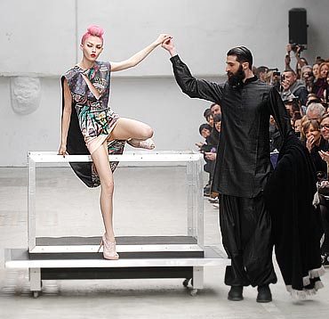 Illusionist Benjamin Dukhan performs a magic trick with a model in one of Arora's latest creations on the runway at Paris FW, March 2