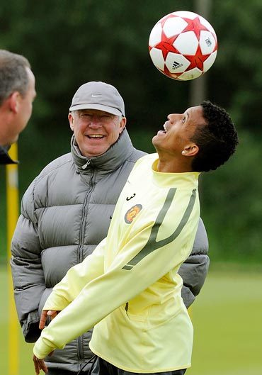 Manchester United's Nani (R) heads the ball watched by coach Alex Ferguson during a practice session at the club's Carrington training ground in Manchester, northern England