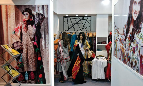 Exhibitors from Pakistan prepare their stall of clothing at the Lifestyle Pakistan Exhibition in New Delhi April 12, 2012. From gourmet chefs to fashion houses showcasing muslin suits on the catwalk, Pakistan will unveil a trade fair in New Delhi on Thursday to reveal a soft side to traditional foe India as commercial ties between the nuclear-armed rivals begin to bloom.