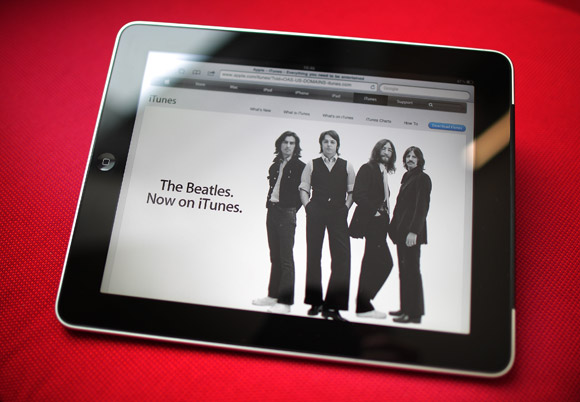 An Apple iPad tablet displays a web page from the iTunes store