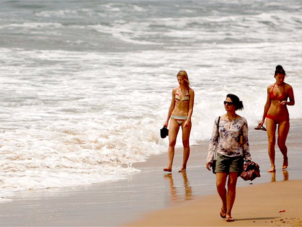 Tourists walk on the Anjuna beach in Goa