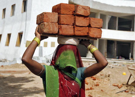 A labourer carries bricks at a residential complex under construction on the outskirts of Ahmedabad.