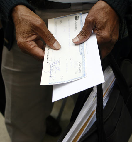 A man holds a cheque after withdrawing money from an IndyMac Bank branch under federal management at the company's corporate headquarters in Pasadena, California July 14, 2008. Regulators seized Pasadena-based IndyMac on Friday after a bank run in which customers withdrew $1.3 billion of deposits over 11 business days, as worries about the company's survival grew, regulators said.