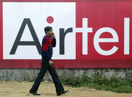 A boy talks on a mobile phone as he walks past a billboard of Bharti Airtel