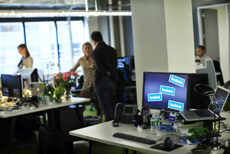Facebook workers stand at their desks before a news conference at their office in New York December 2, 2011.