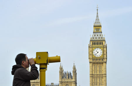 A man looks through a telescope opposite Big Ben and the Houses of Parliament, in central London