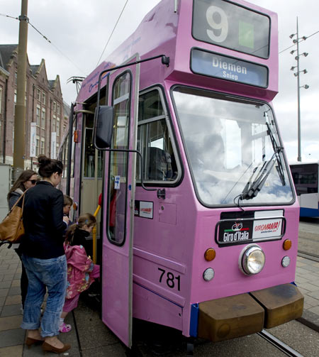 A woman and her children board a tram painted pink in Amsterdam to celebrate the arrival of the Giro d'Italia in Amsterdam
