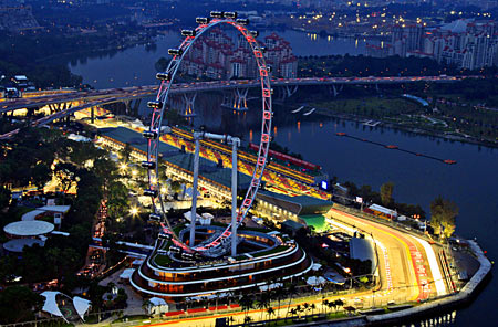 An aerial view shows the main grand stand and the F1 pit building behind the Singapore Flyer observation wheel at dusk