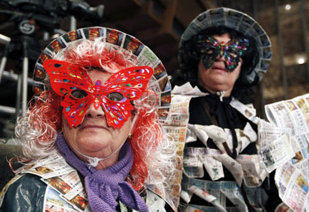 Women in costumes adorned with old lottery tickets attend the draw for Spain's Christmas Lottery