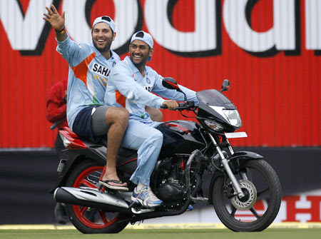 Yuvraj Singh (L) and India's captain Mahendra Singh Dhoni ride a bike which was given to Yuvraj Singh for winning the man-of-the-match award following India's win in the second one-day international cricket match against England in Indore.