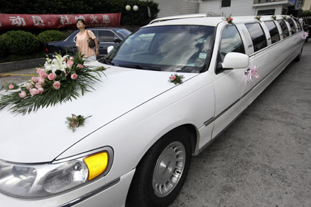 A woman looks on near a Lincoln limousine ferrying a couple for their wedding