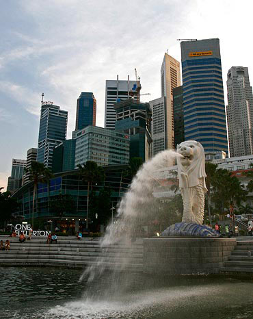 People sit on the steps near the Merlion, in Singapore's financial district