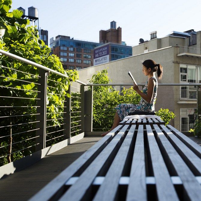 A woman uses the late afternoon sun to read while sitting on the High Line park in New York.